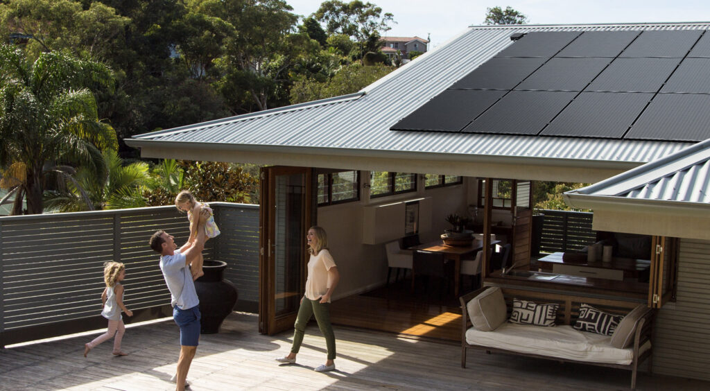 Family playing near house with solar panels installed